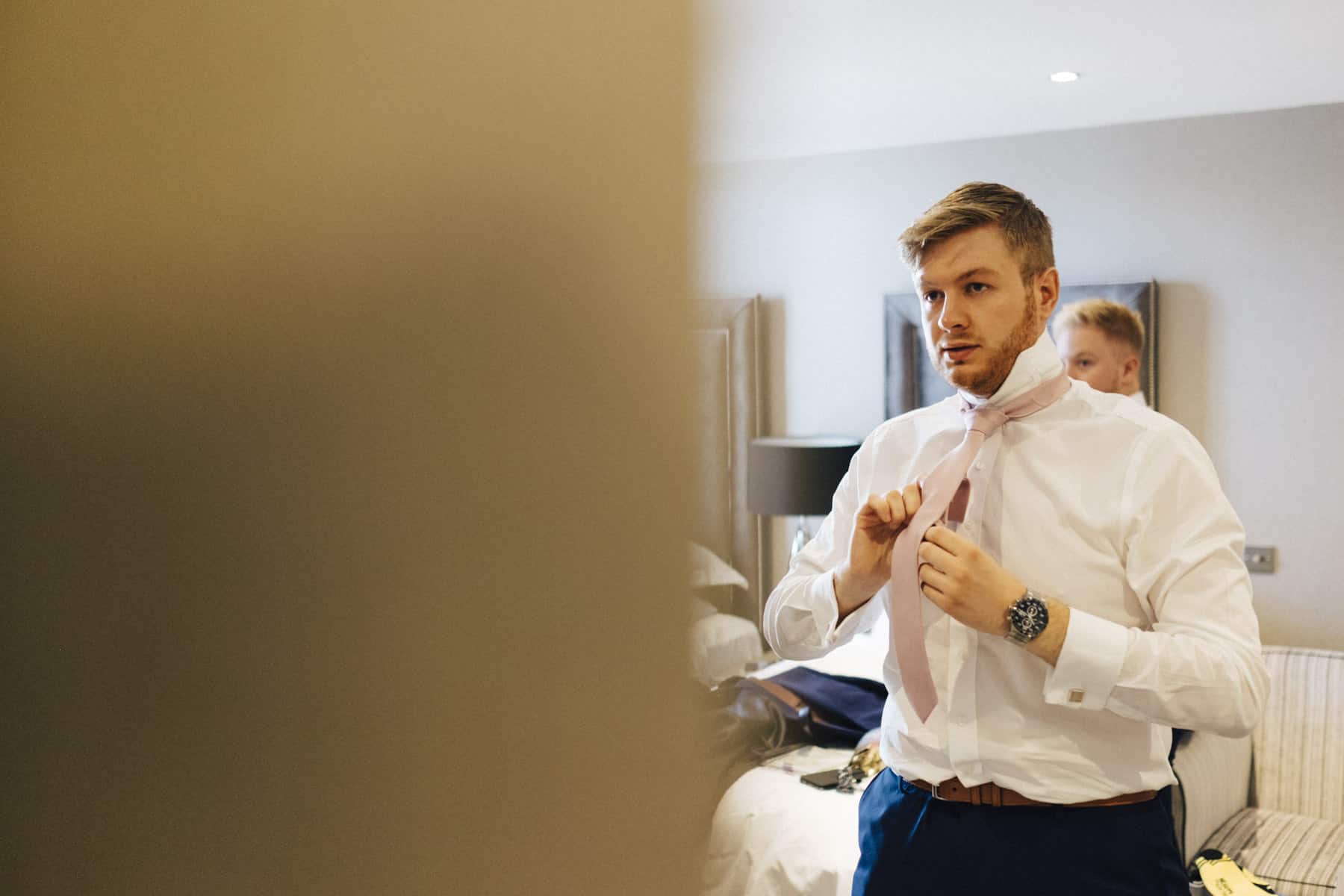Groom doing up his tie